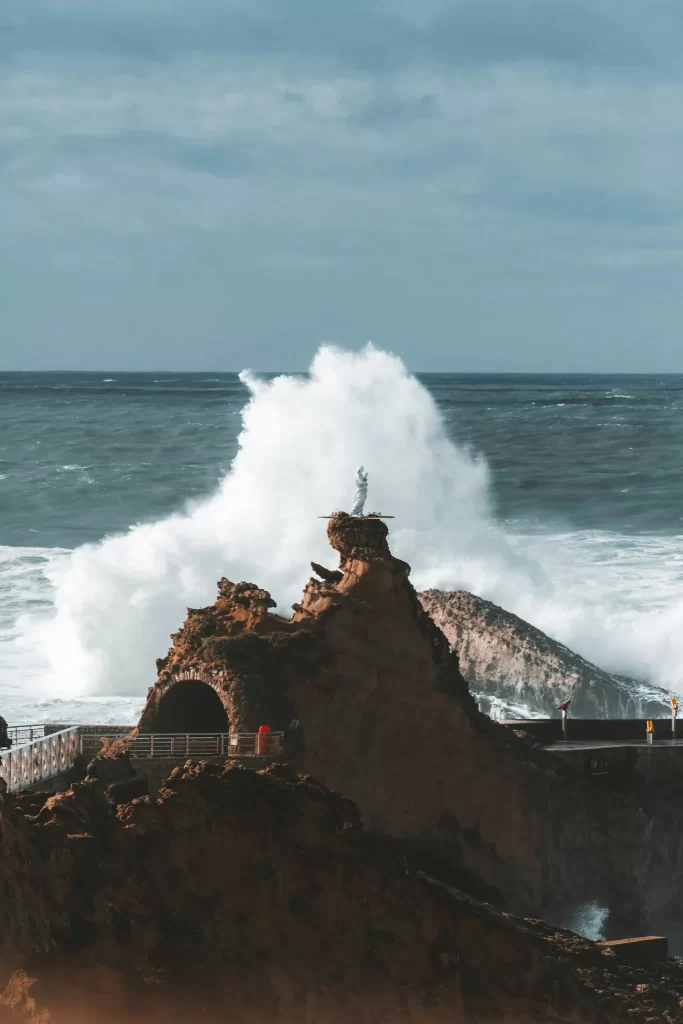 Statue de la Vierge sur le Rocher de Biarritz avec une vague en arrière-plan.