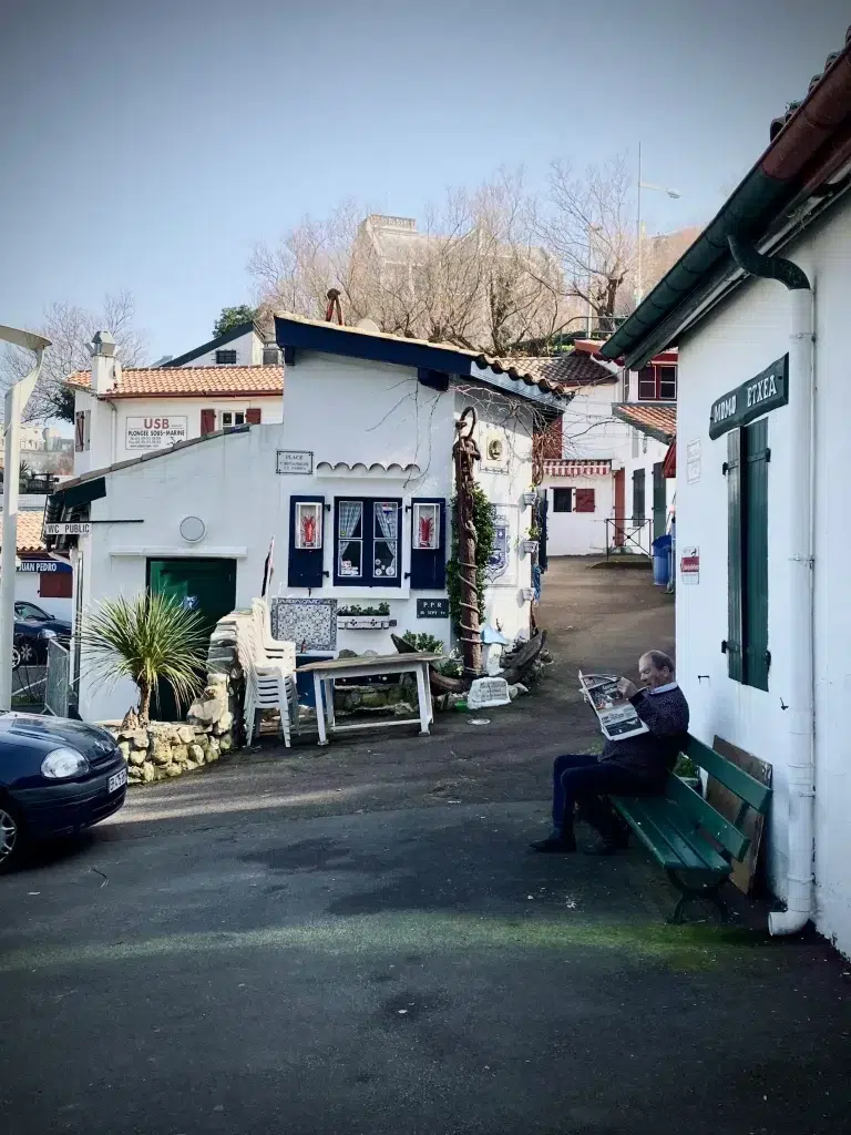 Petit village pittoresque à Biarritz avec un habitant lisant sur un banc