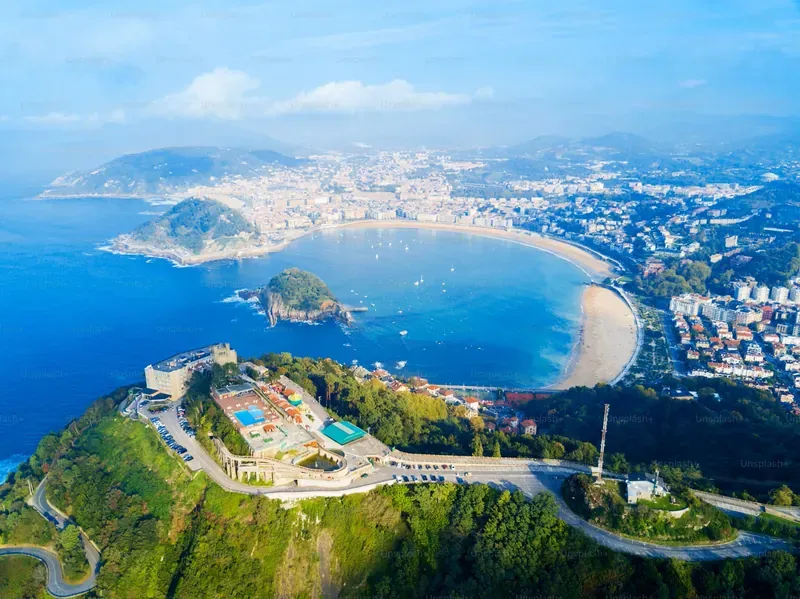 Aerial view of San Sebastian with La Concha Bay, Monte Igueldo, and cityscape on a sunny day