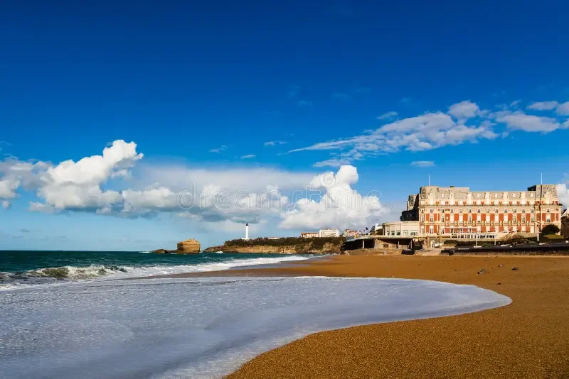 Grande Plage de Biarritz avec l’Hôtel du Palais en arrière-plan sous un ciel partiellement nuageux
