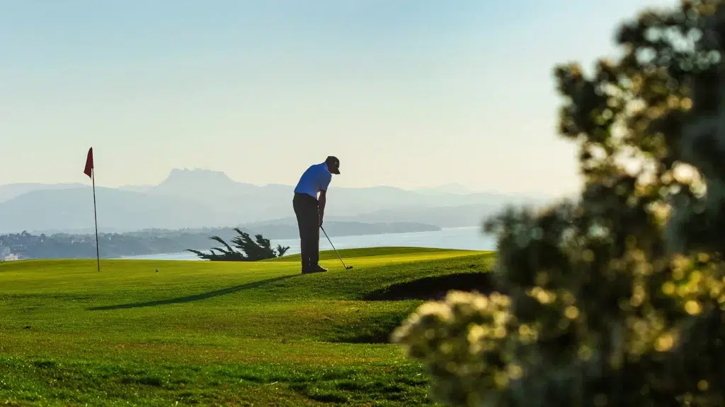 Joueur de golf au Golf d’Ilbarritz, avec une vue panoramique sur l’océan Atlantique et les montagnes